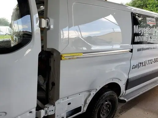 White U-Haul van with open side door; advertisement for moving services visible.
