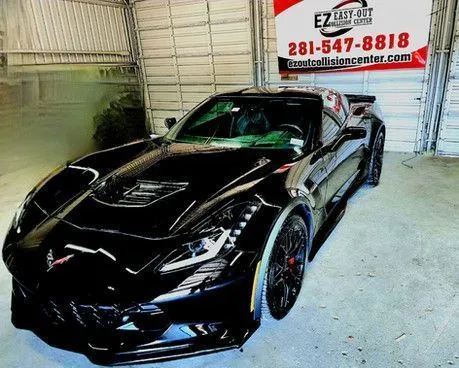 Repaired black Corvette in front of the Easy Out Collision Center banner, three-quarter view